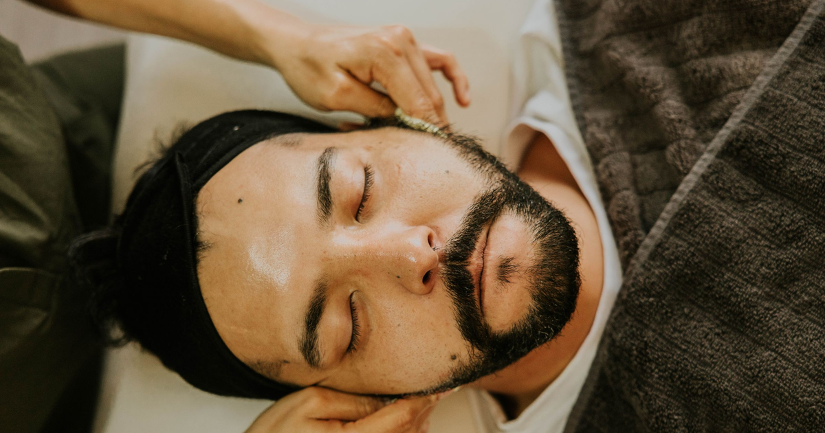 Man relaxing during a professional facial massage in a salon treatment room