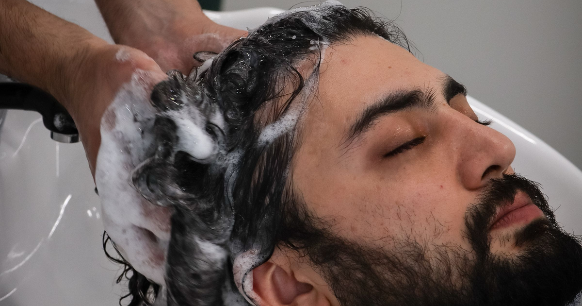 Man relaxing at a salon wash basin during a hair spa for men with a lathered scalp cleanse