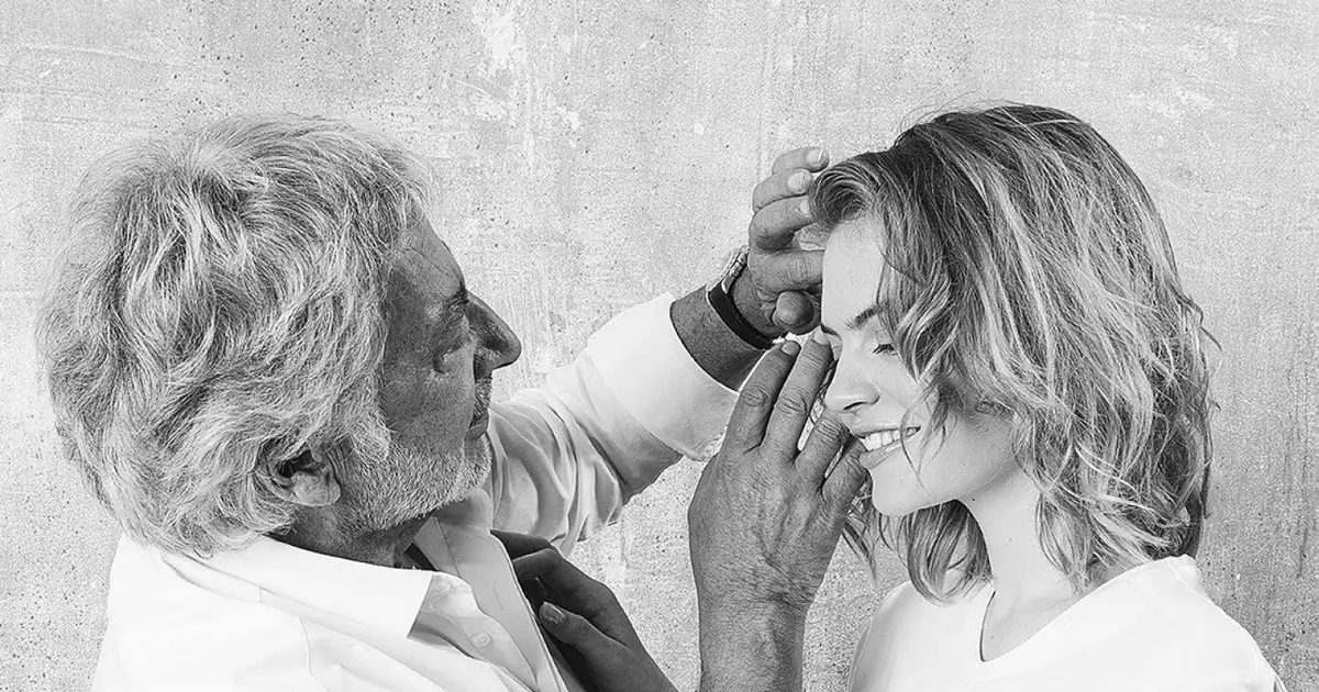 Senior hair stylist carefully shaping a model's hair in a black and white salon portrait